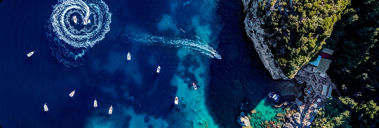 Aerial view of boats in a turquoise bay along a rocky coastline